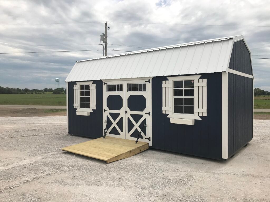 Navy Burnett lofted barn with white trim and a wooden ramp at the doors